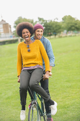 Couple riding bicycle together in park