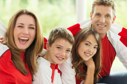 Family In Sports Jerseys Cheering In Living Room