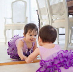 Obraz premium Baby girl admiring herself in mirror
