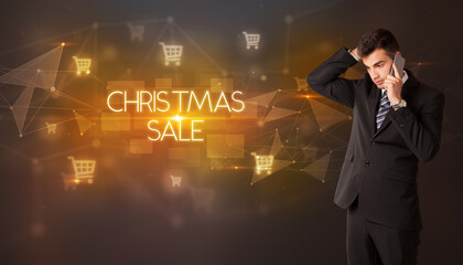 Businessman with shopping cart icons and CHRISTMAS SALE inscription, online shopping concept