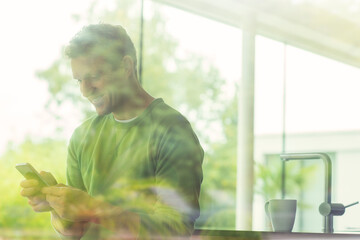 Man using cell phone viewed through window