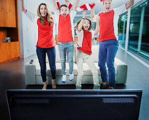 Family cheering in front of television in living room