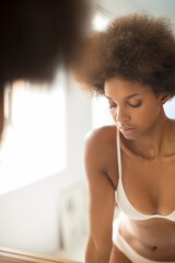 Fototapeta na wymiar Woman in bra standing at bathroom mirror