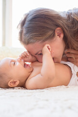 Obraz na płótnie Canvas Mother blowing raspberries on baby's stomach