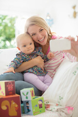 Obraz na płótnie Canvas Mother taking self-portrait with baby girl