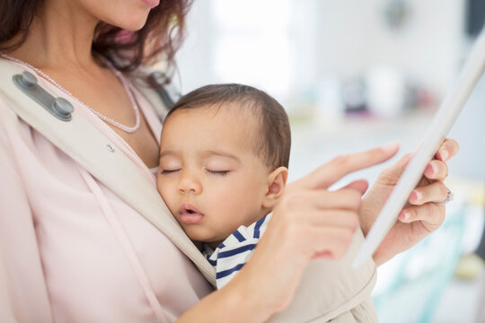 Mother with sleeping baby girl using digital tablet