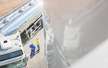Workers talking next to stainless steel milk tanker