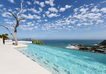 Clouds in blue sky over luxury lap pool overlooking ocean