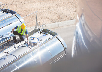 Worker on platform above stainless steel milk tanker