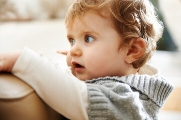 Baby girl clinging to edge of sofa