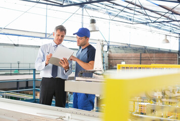 Supervisor and worker with clipboard in food processing plant - obrazy, fototapety, plakaty