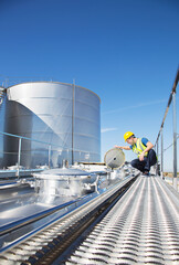 Worker on platform above stainless steel milk tanker