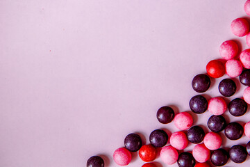 Violet background with round pink, purple and red candys on the right side. Top view with copy space