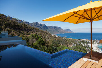View of ocean from sunny patio with infinity pool
