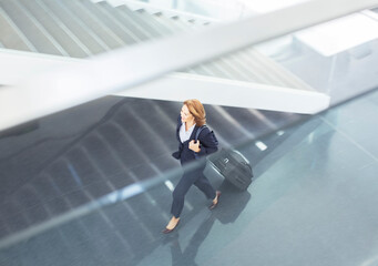 Businesswoman pulling suitcase in lobby