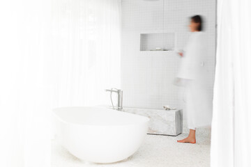 Fototapeta na wymiar Blurred view of woman walking in modern bathroom