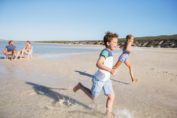 Children running in waves on beach 