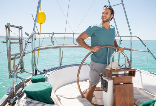 Man Steering Sailboat On Water