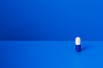Prescription pill standing upright on blue counter