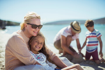 Fototapeta na wymiar Grandmother hugging granddaughter on beach