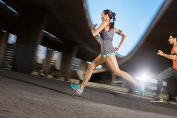 Fototapeta premium Couple running through city streets together