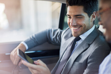 Businessmen looking at cell phone in car 