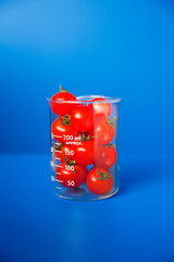 Obraz premium Beaker of small tomatoes on blue counter