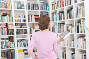 Woman selecting book from library