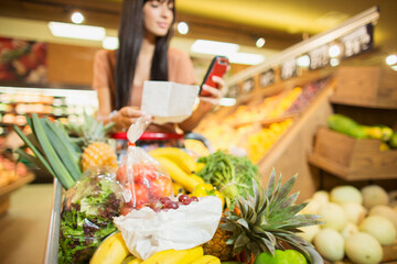 Woman checking shopping list in grocery store