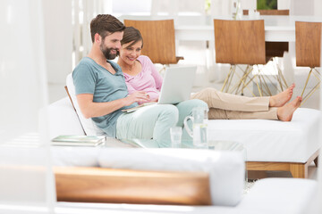 Couple using laptop together on daybed in modern living room