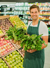 Clerk carrying basket of produce in grocery store