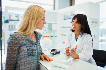 Woman discussing product with pharmacist in drugstore