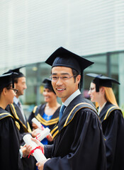 Student in cap and gown standing with friends