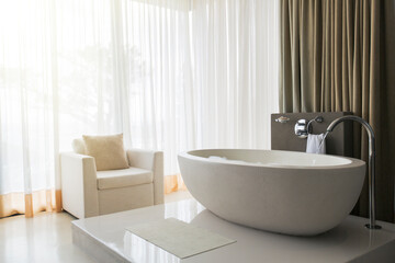 Obraz na płótnie Canvas View of modern and luxurious bathroom with bathtub and armchair