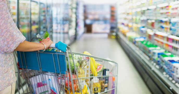 Woman pushing full shopping cart in grocery store
