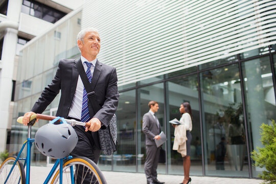 Businessman walking bicycle outside of office building