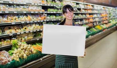 Clerk holding blank card in produce section of grocery store