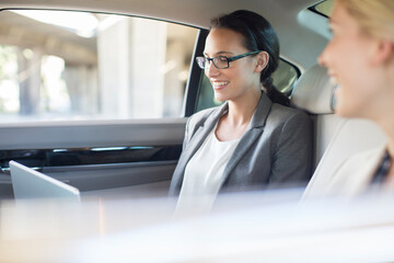 Businesswomen working in car back seat