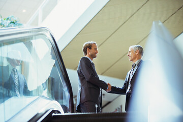 Businessmen shaking hands at top of stairs of office building