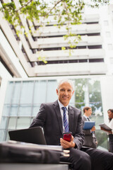 Businessman working on bench outside of office building