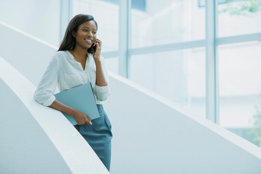 Businesswoman Talking On Cell Phone On Office Building Stairs