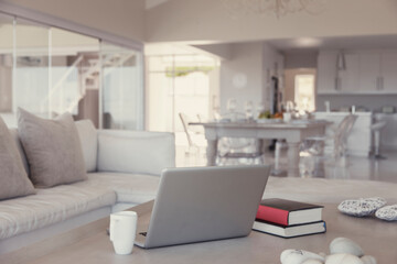 Modern living room interior with laptop, books and mug on table