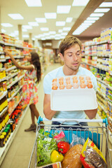 Man examining carton of eggs in grocery store