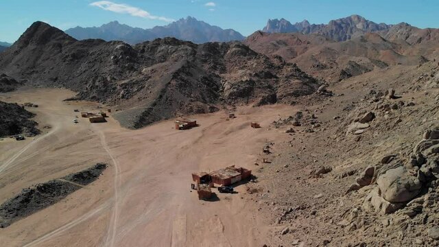 Top view of the Sahara desert, desert mountains. Wooden Bedouin houses. Sands. Tourists walk around the village.