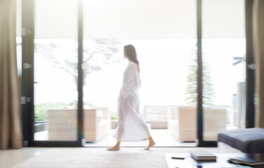 Woman in bathrobe walking through living room