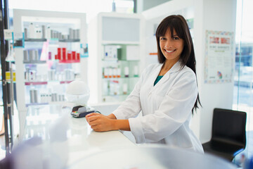 Pharmacist smiling behind counter in drugstore