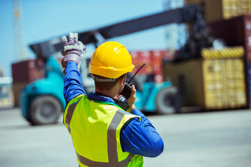 Worker using walkie-talkie near cargo containers