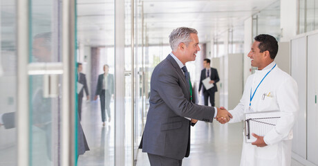 Scientist and businessman shaking hands in hallway