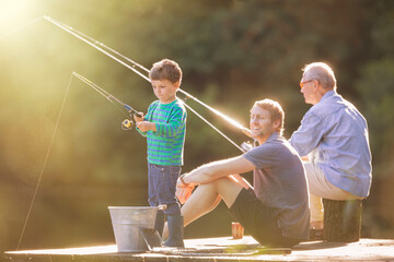 Boy, father and grandfather fishing on wooden dock