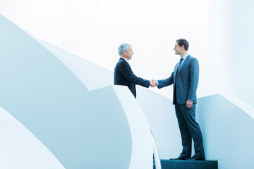 Businessmen shaking hands on staircase of office building